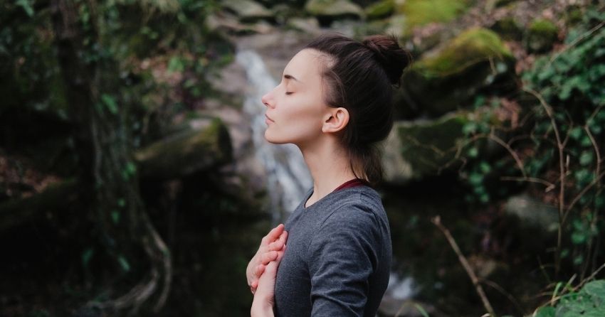 woman breathing in nature; mindfulness with paced breathing lowers blood pressure.