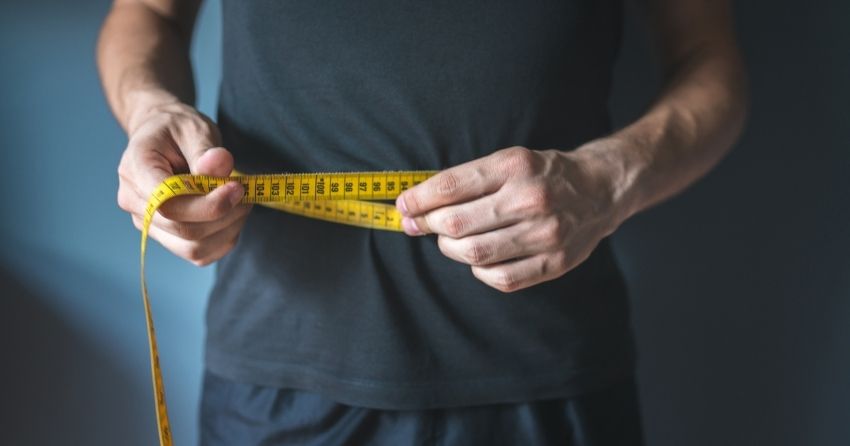 transplanting brown fat cells may be a promising treatment for obesity and diabetes; man is measuring his waist circumference