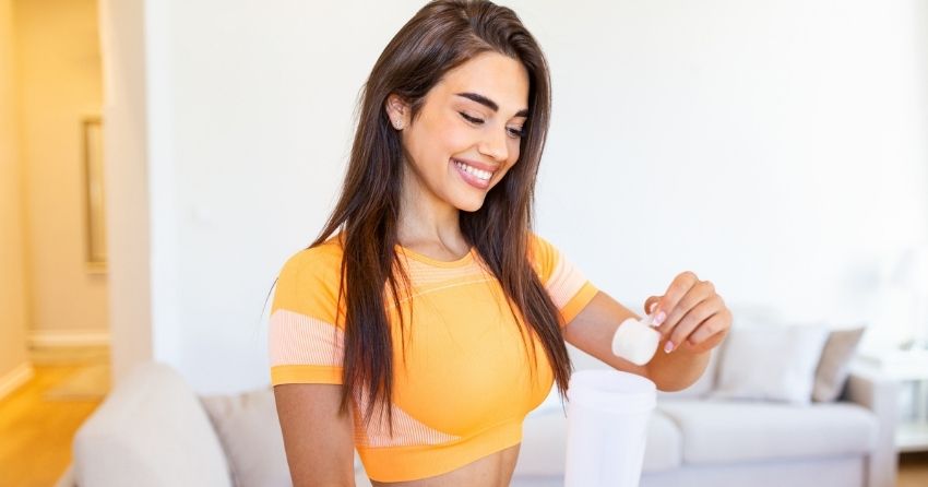 A youthful woman pouring a scoop of NMN Pro Complete powder into a shaker jar