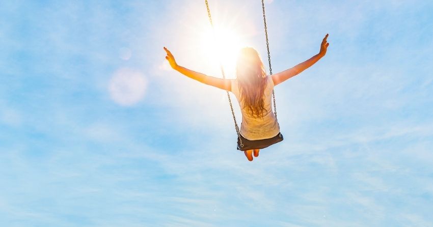 woman on swing in sun; Moderate sunlight exposure is linked to several health benefits. 